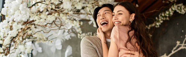 A couple shares laughter and love while getting ready for their wedding amid blossoming flowers.