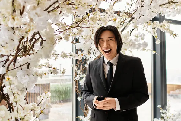 Gülümseyen genç bir damat düğün gününde çiçek aranjmanlarının yanında durur..