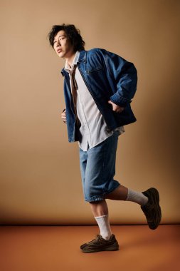 Havalı bir Asyalı, bahar kıyafetleri trendlerinin altını çizerek stüdyoda güven içinde poz veriyor..