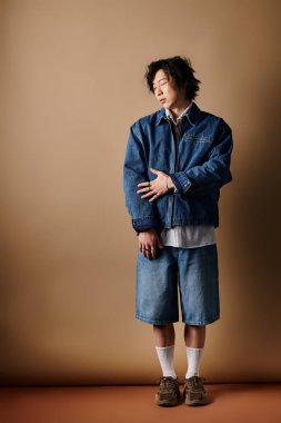 Genç bir adam modern bahar modasını şık bir stüdyo ortamında sergiliyor..