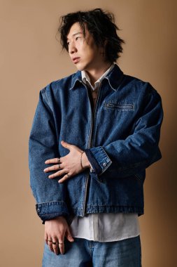 Asyalı bir adam kendine güvenerek stüdyoda duruyor ve şık bahar modasını sergiliyor..