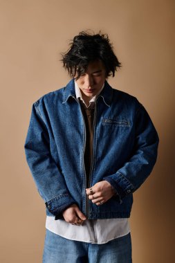 Asyalı bir adam şık bahar kıyafetleri içinde, modern moda atmosferleri yayarak rahatça poz verir..