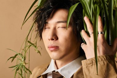 Modayı takip eden bir adam, bir stüdyoda bahar modasının özünü somutlaştıran yeşillikle huzur içinde poz verir..