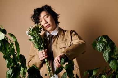 Havalı bir Asyalı stüdyoda poz veriyor, elinde çiçeklerle bahar modasını gösteriyor..