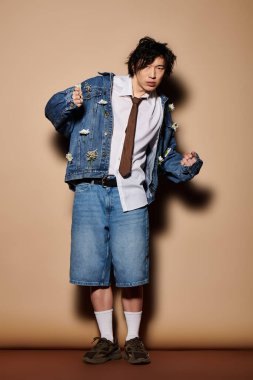 Asyalı bir adam, modern bir stüdyoda eşsiz bir bahar moda topluluğu sergiliyor..