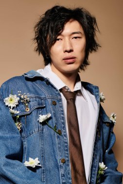 Şık bir Asyalı, çiçek aksanlı bir stüdyoda bahar modasına modellik yapıyor. Modern bir zarafet yayıyor..