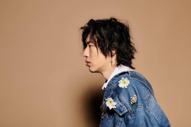 Asyalı bir adam kendine güveni olan şık bir bahar elbisesi ve çiçek aksanıyla stüdyo ortamında dolaşır..