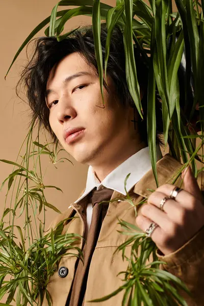 Asyalı bir adam bereketli yeşilliklerle çevrili şık bahar kıyafetlerine güveniyor..