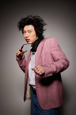 Şık Asyalı bir adam, bahar mevsiminde eşsiz bir yeteneği olan şık bir kıyafetin içinde özgüvenle poz verir..