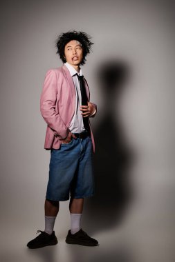 Yüzünde kan olan Asyalı bir adam modern stüdyo ortamında modaya uygun bahar kıyafetleri sergiliyor..