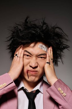 Yüzünde kan olan Asyalı bir adamın baş ağrısı ve eşsiz bir tarzı var.