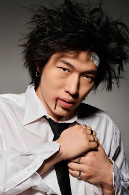 Yüzünde kan olan Asyalı bir adam stüdyoda moda bahar kıyafetleri sergiliyor, kendine güveni ve tarzı var..