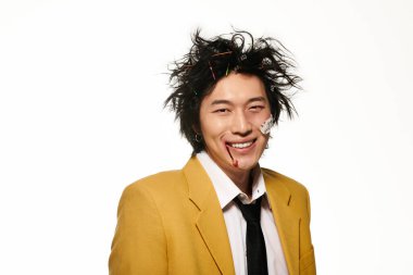 Yüzünde kan olan Asyalı bir adam gülümsüyor ve modaya uygun bahar kıyafetleri giyiyor.