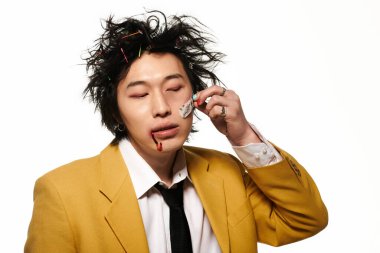 Yüzünde kan olan Asyalı bir adam bahar stüdyosunda sarı bir takım elbiseyle poz veriyor..