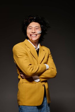 Yüzünde kan olan Asyalı bir adam modern stüdyo ortamında neşeli bir gülümsemeyle moda bahar modasını sergiliyor..