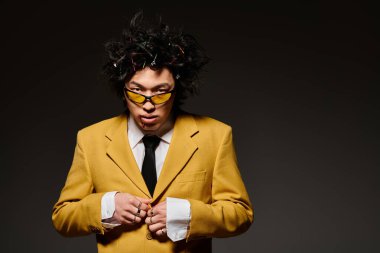 Yüzünde kan olan Asyalı bir adam şık bahar kıyafetleri içinde minimalist bir stüdyoda rahatça poz veriyor..