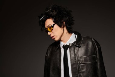 Asyalı bir adam şık bir bahar modasını dramatik ışıklandırmalı şık bir stüdyoda sergiliyor..