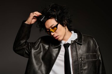 Bir adam zarif bir şekilde stüdyoda poz veriyor, modaya uygun moda tarzını özgüvenle sergiliyor..