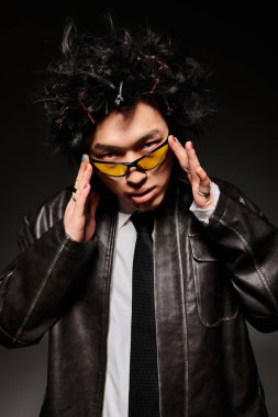 Yüzünde kan olan Asyalı bir adam, çarpıcı bir saç stili ve bahar modasını yansıtan modaya uygun bir kıyafet sergiliyor..