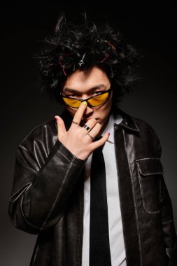 Şık kıyafetler giyen Asyalı bir adam şık bir stüdyo ortamında güven içinde poz veriyor..