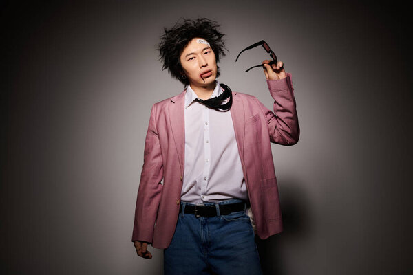 An asian man with blood on face showcases trendy clothing with a confident expression in a studio during spring.