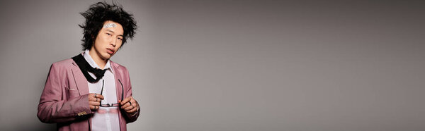 A fashionable Asian man with blood on face poses confidently in a studio, embracing spring style with flair, banner