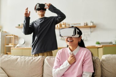 Genç Asyalı bir çift rahat evlerinde sanal gerçekliği deneyimliyor, gülüyor ve neşeyi paylaşıyorlar..