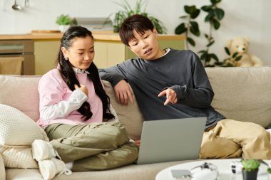 Genç bir çift, sıcak bir ev atmosferiyle çevrili dizüstü bilgisayarlarıyla neşeyle meşgul oluyor..