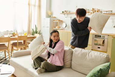 Neşeli bir çift, keyifli bir yastık kavgası yapar rahat oturma odalarında, kahkahalarla.