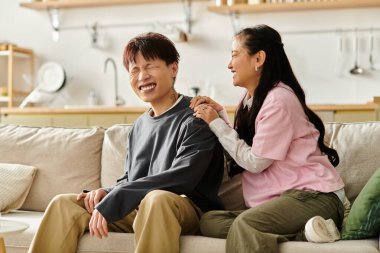 Genç bir Asyalı çift evde dinlenirken gülüyor ve şakalaşıyor..