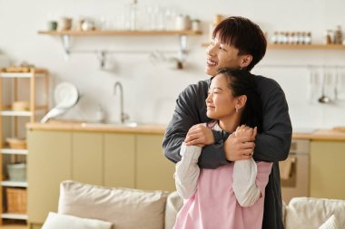 Neşeli genç çift, sevgi ve sıcaklıkla dolu şık evlerinde şefkatli bir kucaklaşmanın tadını çıkarıyor..