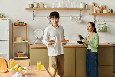 Mutlu bir Asyalı çift, davet ettikleri mutfakta ev yapımı kahvaltıdan zevk alır..