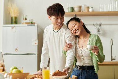 Genç bir çift, sıcak mutfaklarında birlikte kahvaltı ederken kahkahalarını paylaşıyor..