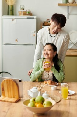 Genç bir Asyalı çift keyifli bir kahvaltı yapar, birlikte güler ve lezzetli yemekleri paylaşırlar..