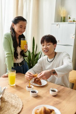 Genç bir çift evde keyifli bir kahvaltı yapar, kruvasan ve içeceklerin tadını çıkarırlar..