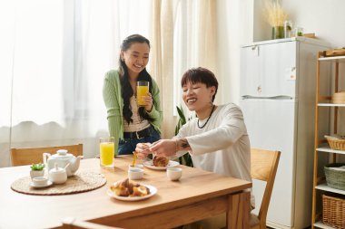 Genç bir çift evde keyifli bir kahvaltı yapar, birlikte gülümseme ve yemek paylaşırlar..