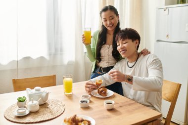 Genç bir Asyalı çift birlikte sıcak bir kahvaltı yapar, kahkaha ve yemek paylaşırlar..