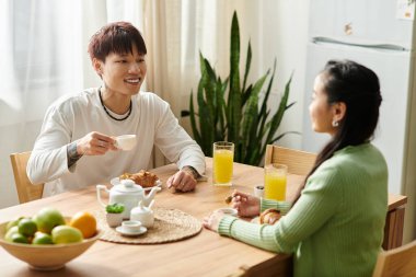 Genç çift kahvaltıdan zevk alıyor, lezzetli yemeklerin ve evde sıcak içeceklerin tadını çıkarıyor..