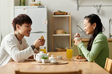 Genç bir çift, neşeli güneş ışığıyla çevrili keyifli bir kahvaltıdan zevk alır..