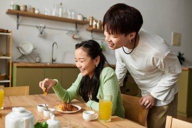 Kahkahalar atarak ve lezzetli bir kahvaltıyı paylaşarak, genç bir çift sabah yemeğinin tadını çıkarıyor..