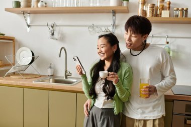 Genç bir çift kahvaltının tadını çıkarırken aynı zamanda kahkahalarını ve telefon ekranını paylaşıyor..