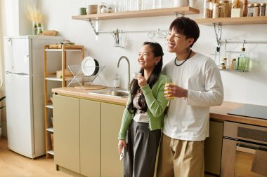 Genç bir çift aydınlık mutfaklarında hafif bir kahvaltıdan zevk alır, gülümsemelerini ve kahkahalarını paylaşırlar..