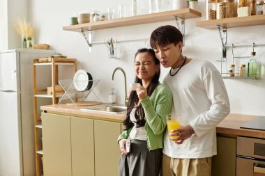 Genç bir çift kahvaltıdan zevk alıyor, gülümsüyor ve sıcak evlerinin mutfağında içkilerini paylaşıyor..