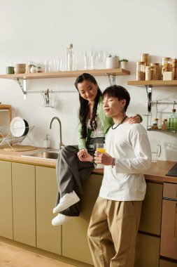 Genç Asyalı bir çift, birlikte sıcak bir kahvaltı yaparken, parlak mutfaklarında dinleniyor..