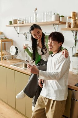 Genç çift sıcaklıkla dolu aydınlık bir mutfakta otururken birlikte kahvaltıdan zevk alıyor..