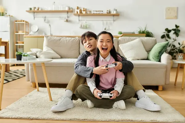 Genç bir çift yerde oturmuş, modern yaşam alanlarında oyun oynuyorlar..