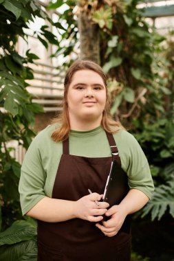 İşiyle meşgul olan Down sendromlu genç bir kadın yemyeşil ortamda kendine güvenini sergiliyor..