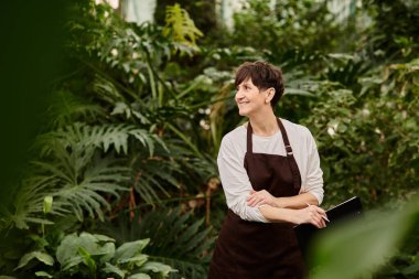 Yetişkinlik çağında kendine güvenen bir kadın, yemyeşil bir serada çalışmaktan zevk alır..