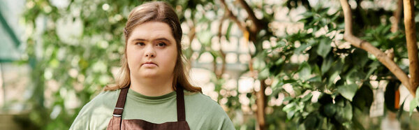 Confident young woman with Down syndrome works in greenhouse, nurturing plants and enjoying nature.