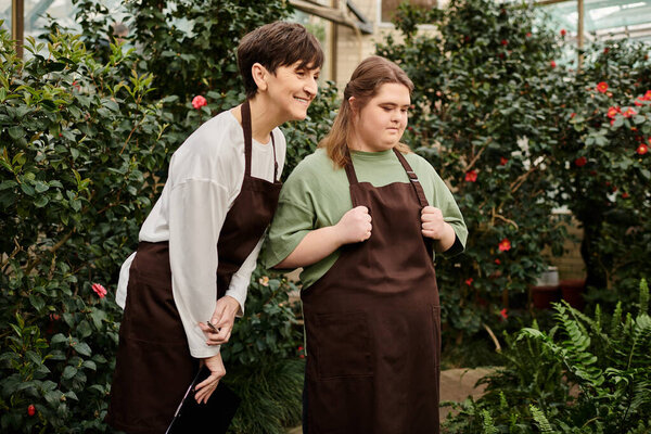 В живой оранжерее зрелая женщина делится идеями со своим молодым коллегой с синдромом Дауна.